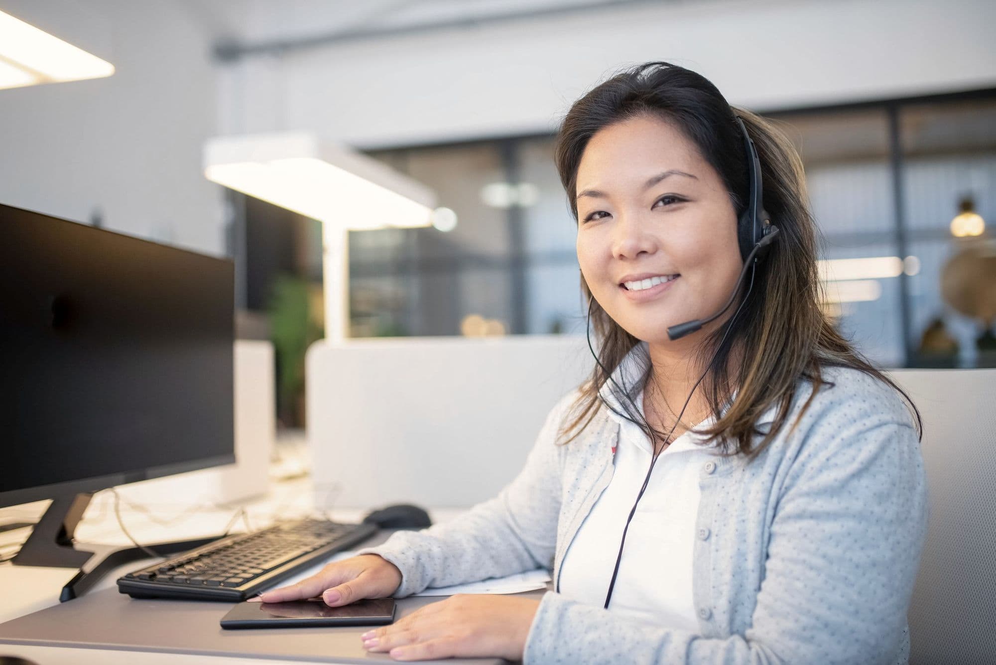 A receptionist on a headset taking a call at her desk.
